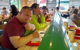 Zdjęcie przedstawia pomieszczenie restauracji McDonald's, w kt&oacute;rym przy stole siedzi mężczyzna oraz dwie kobiety 
