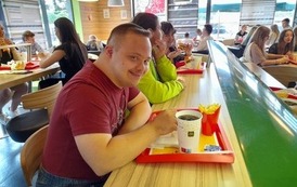 Zdjęcie przedstawia pomieszczenie restauracji McDonald's, w kt&oacute;rym przy stole siedzi mężczyzna oraz dwie kobiety 