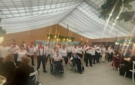 Na zdjęciu grupa kobiet i mężczyzn ubrana w białe koszule i czerwone oraz niebieskie muchy