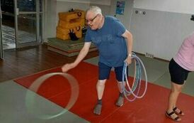 Na zdjęciu mężczyzna toczący po podłodze hula hop