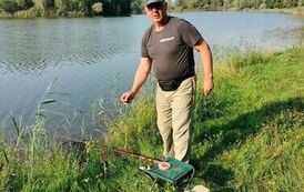 Mężczyzna stojący nad wodą, obok leży wędka