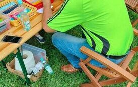 Mężczyzna siedzący przy stole i skręcający kolorowe paski z papieru igłą do quillingu