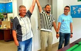 Na zdjęciu trzech mężczyzn tzrymających się za ręce, dwaj z nich mają ręce uniesione do g&oacute;ry