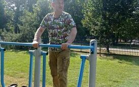 Mężczyzna stojący na urządzeniu fitness zewnętrznym (wahadle)