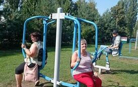 Dwie kobiety siedzą na urządzeniu fitness zewnętrznym