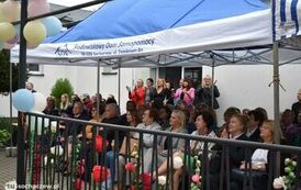 Zdjęcie przedstawia gości siedzących na krzesełkach pod namiotem