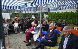 Zdjęcie przedstawia gości siedzących na krzesełkach pod namiotem
