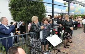 Zdjęcie przedstawia gości siedzących na krzesełkach pod namiotem