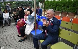Zdjęcie przedstawia gości siedzących na krzesełkach pod namiotem