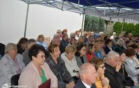Zdjęcie przedstawia gości siedzących na krzesełkach pod namiotem