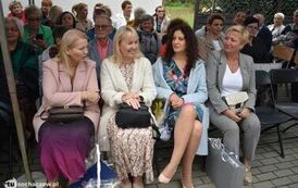 Zdjęcie przedstawia gości siedzących na krzesełkach pod namiotem