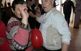 Na zdjęciu kobieta i mężczyzna tańczący w parze, pomiędzy nimi znajduje się balon
