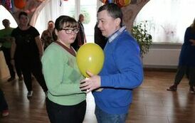 Kobieta i mężczyzna tańczą w parze, pomiędzy nimi znajduje się balon