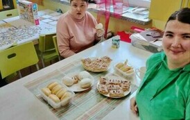 Zdjęcie przedstawia dwie kobiety siedzące przy stole, na kt&oacute;rym są pączki i ciastka