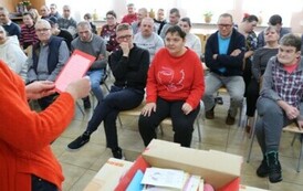 Zdjęcie przedstawia pudełko z kartkami walentynkowymi, w tle siedzą kobiet i mężczyźni