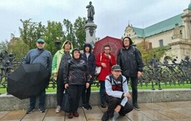 Grupa kobiet i mężczyzn pozuje na tle pomnika Adama Mickiewicza w Warszawie
