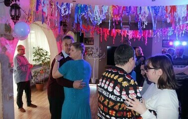 Zdjęcie przedstawia kobiety i mężczyzn tańczących w parach podczas zabawy sylwestrowej