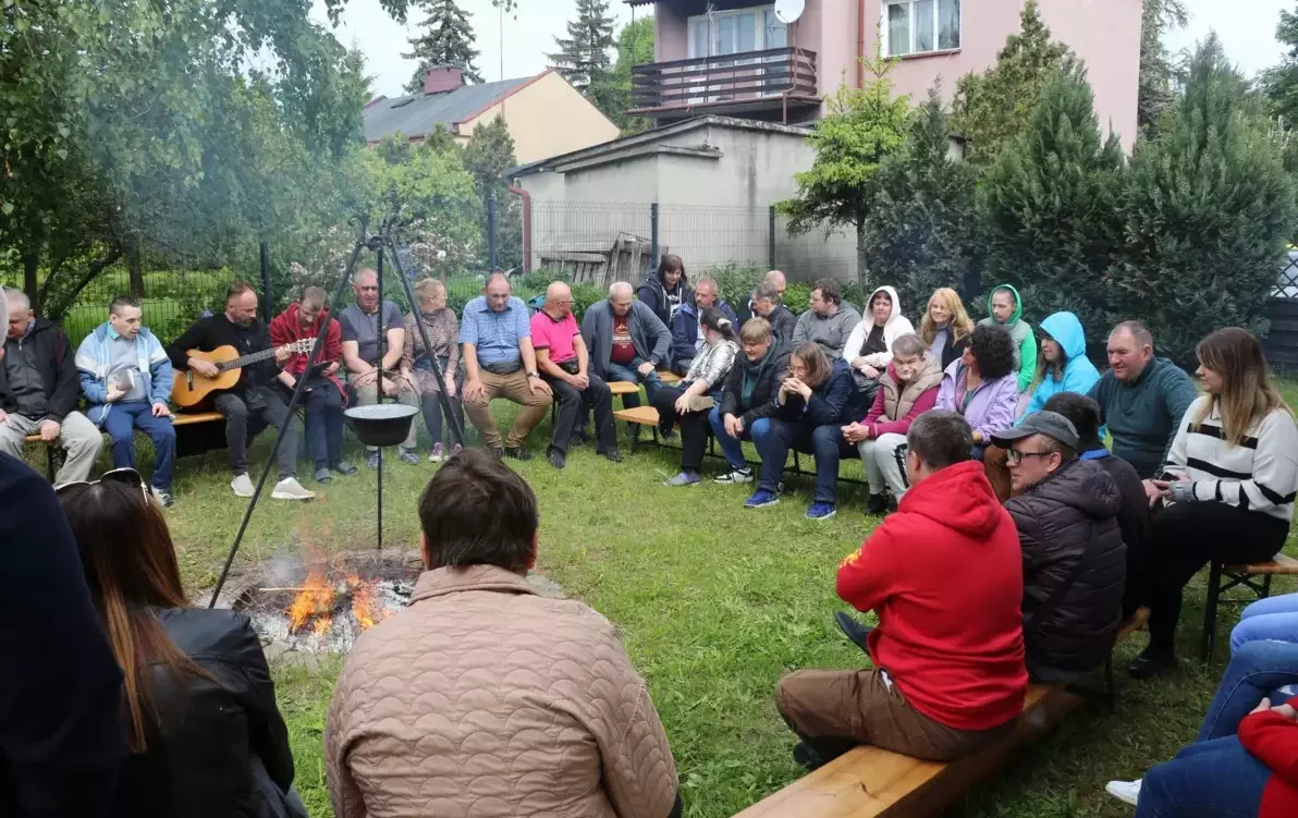 Grupa osób siedzących przy ognisku